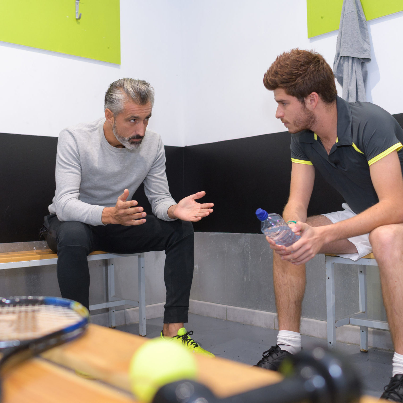 coach talking to tenis player in locker room